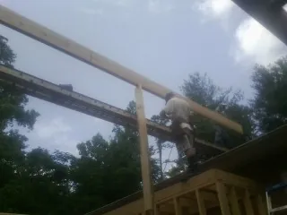 Carpenter setting a ridge beam over a new addition frame — Ice Dam Removal by Roofing Brothers in Pandora