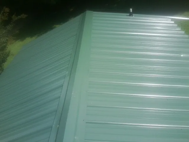 New green metal panels meeting at the ridge of a roof — Flat Roof Repair work by our crew in Pandora