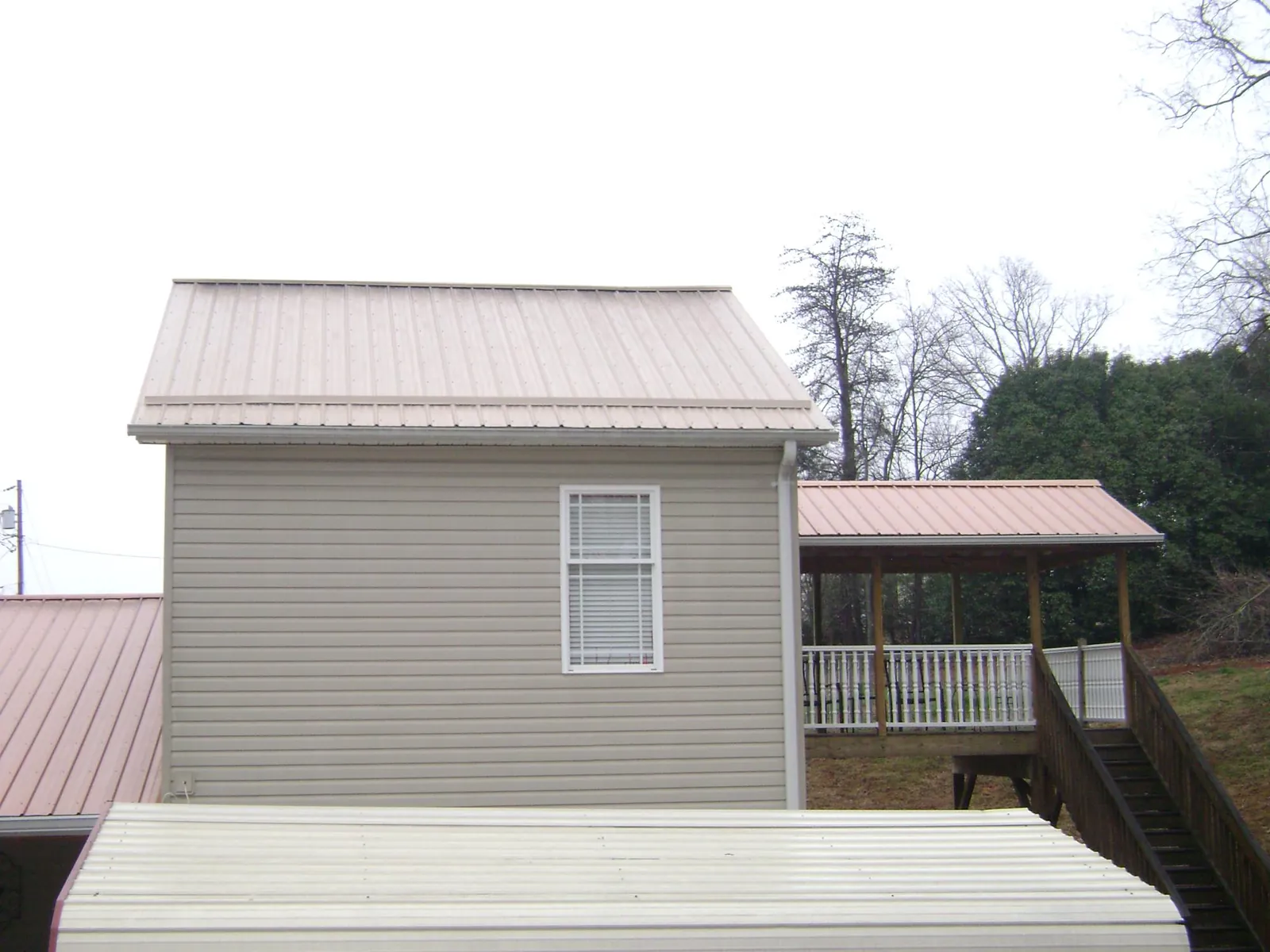 Tan metal roofs on a two story addition and attached porch, from a Roof Replacement job in Pandora